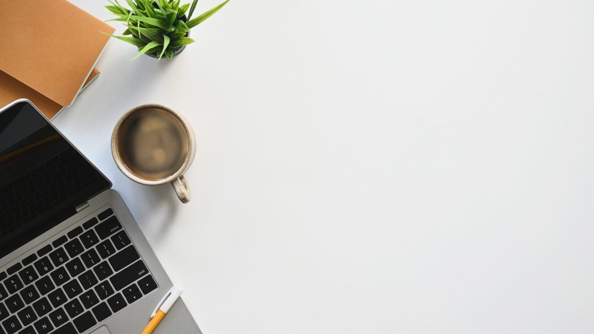 Top view image of white working desk with accessories putting on it. Flat lay Computer laptop, Coffee cup, Potted plant, Notebook. Modern and Orderly style workplace concept.
